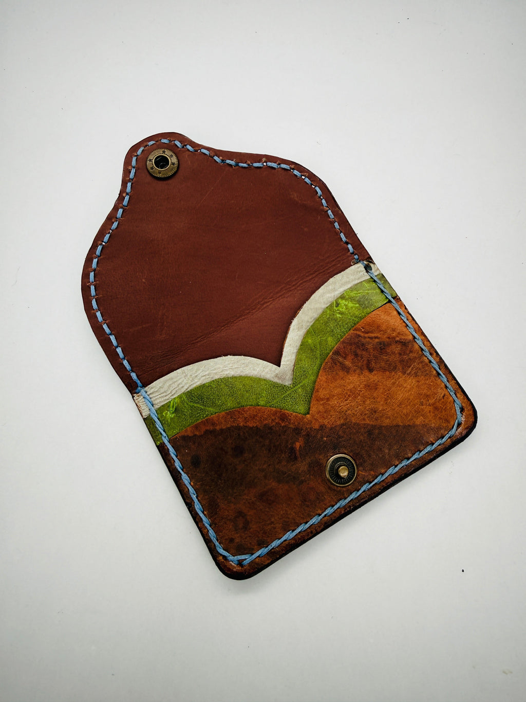 Brown leather pouch with green interior on a white background